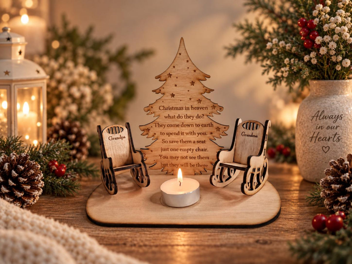 May include: A wooden memorial display featuring two miniature rocking chairs labelled Grandpa and Grandma, a central Christmas tree cutout with the text Christmas in heaven what do they do? They come down to earth to spend it with you. So save them a seat just one empty chair. You may not see them but they will be there, and a small lit tea light candle.