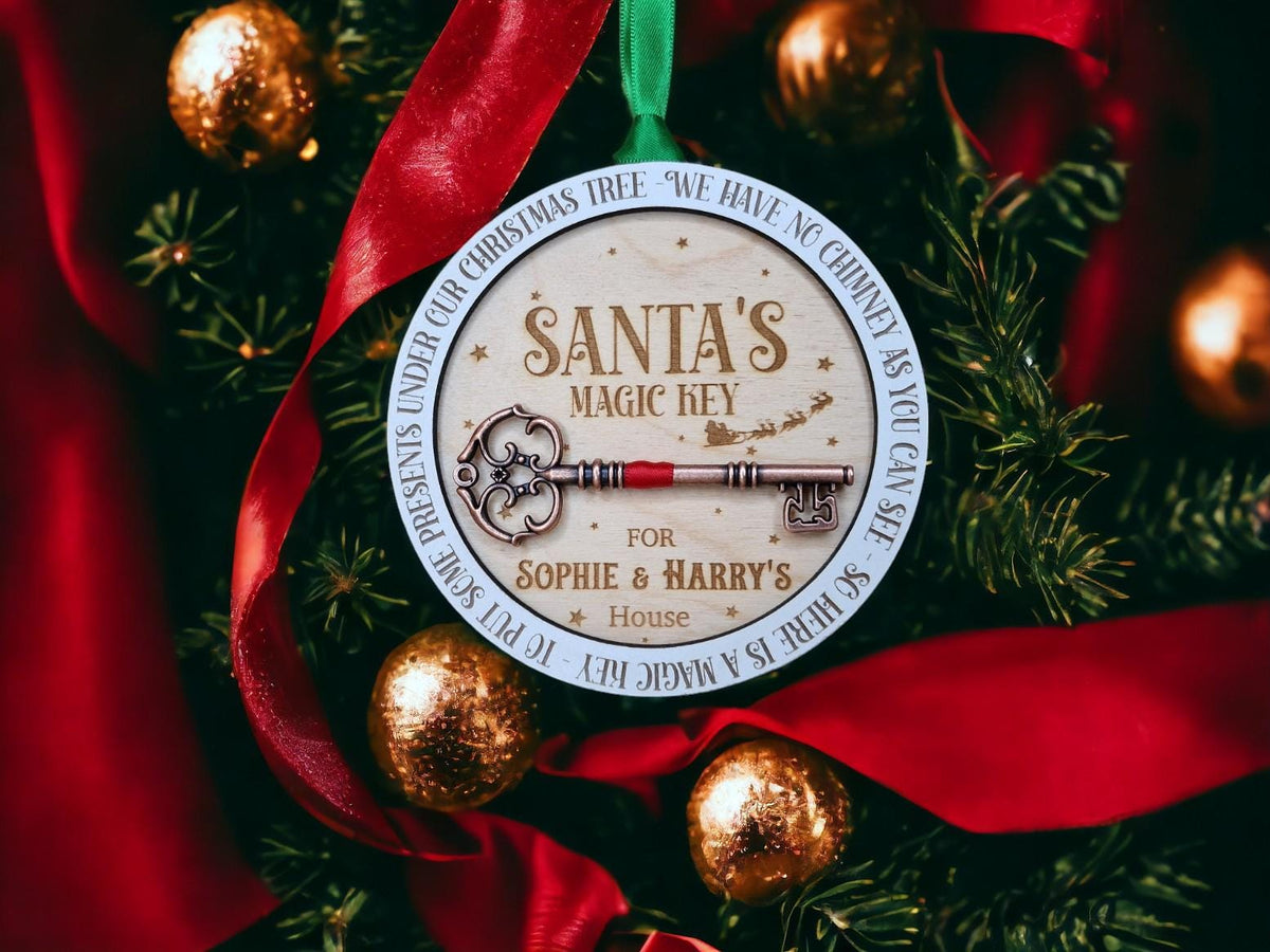 May include: A round wooden Christmas bauble with a white border and the text "Santa's Magic Key" in gold lettering. The ornament features a decorative key with a red ribbon and the text "For Sophie & Harry's House".